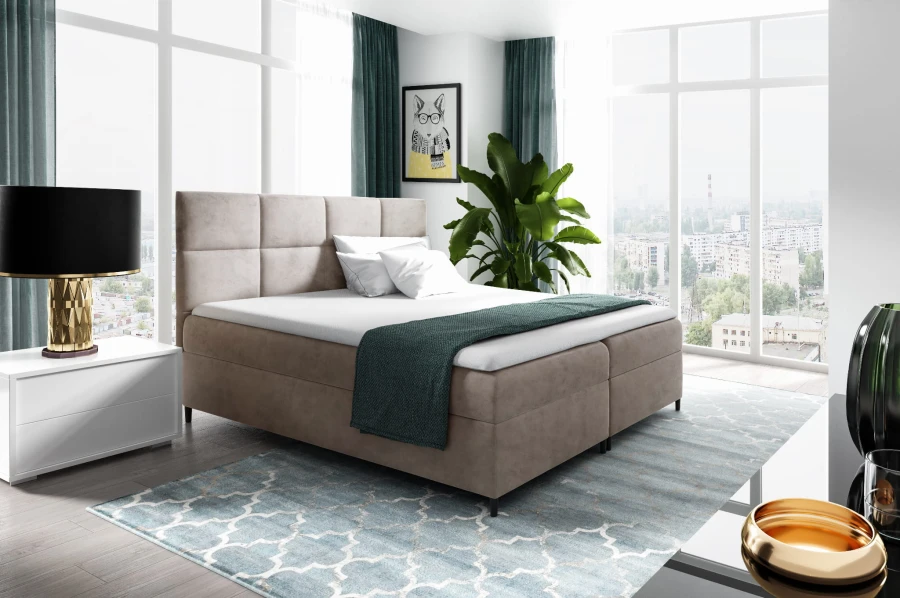 Modernes Boxspringbett in Beige mit gepolstertem Kopfteil in hellem Schlafzimmer.