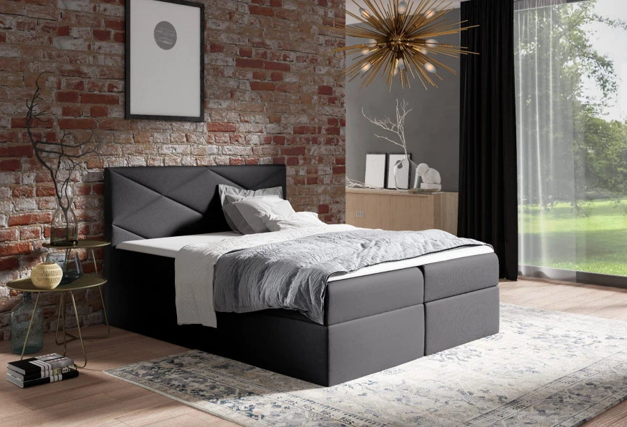 Schwarzes Boxspringbett mit gestepptem Kopfteil vor rustikaler Backsteinwand im Loft-Stil.
