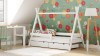 Weißes Kinder-Hausbett aus Holz in einem hellen Kinderzimmer mit floraler Tapete.