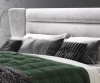 Detailaufnahme der Kissen und des weich gepolsterten Kopfteils eines grauen Boxspringbetts.