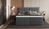 Boxspringbett mit gestepptem Kopfteil in Dunkelgrau im Schlafzimmer.