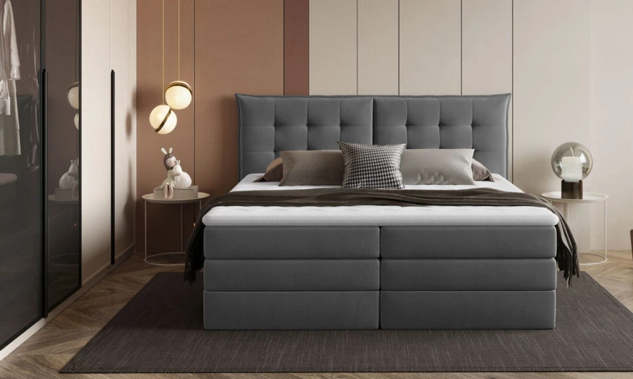 Boxspringbett mit gestepptem Kopfteil in Dunkelgrau im Schlafzimmer.