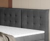 Gepolstertes graues Kopfteil eines Boxspringbettes mit dekorativer Steppung.