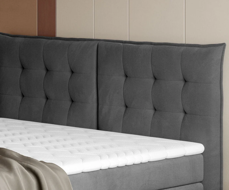 Gepolstertes graues Kopfteil eines Boxspringbettes mit dekorativer Steppung.