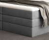 Detailansicht der grauen gepolsterten Basis eines Boxspringbettes mit Matratze.