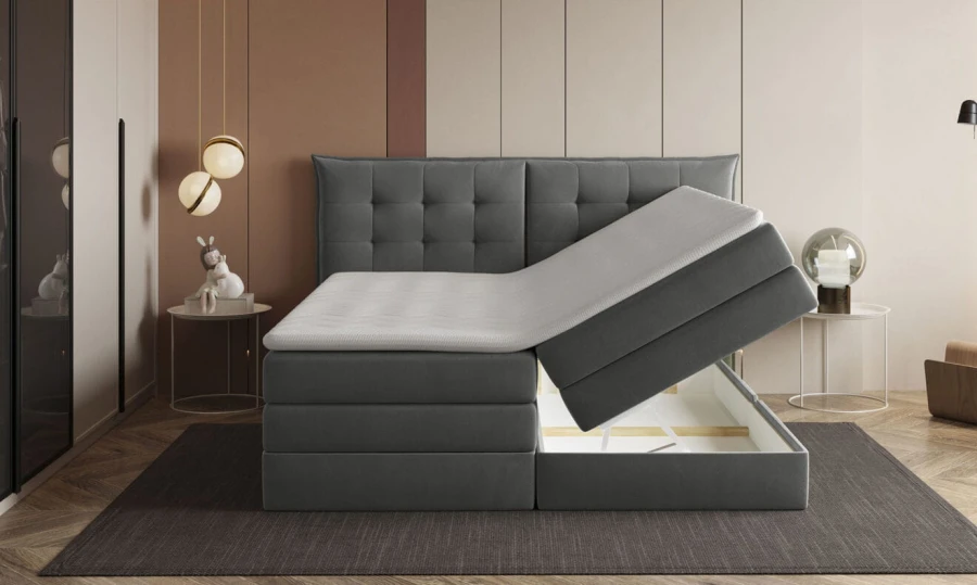 Graues Boxspringbett mit praktischem, seitlich zu öffnendem Bettkasten für Stauraum.