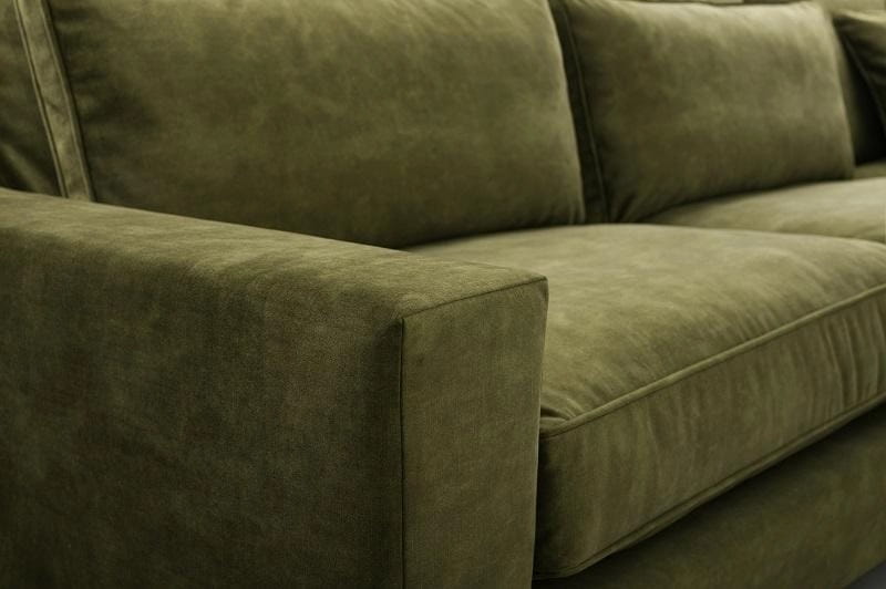 Nahaufnahme des olivgrünen Samtstoffs und der hochwertigen Ziernaht eines Sofas.