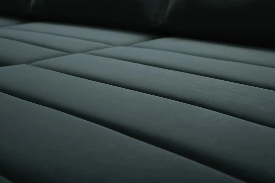Nahaufnahme der hochwertigen, gesteppten Stoffstruktur des dunkelgrünen Samtsofas.
