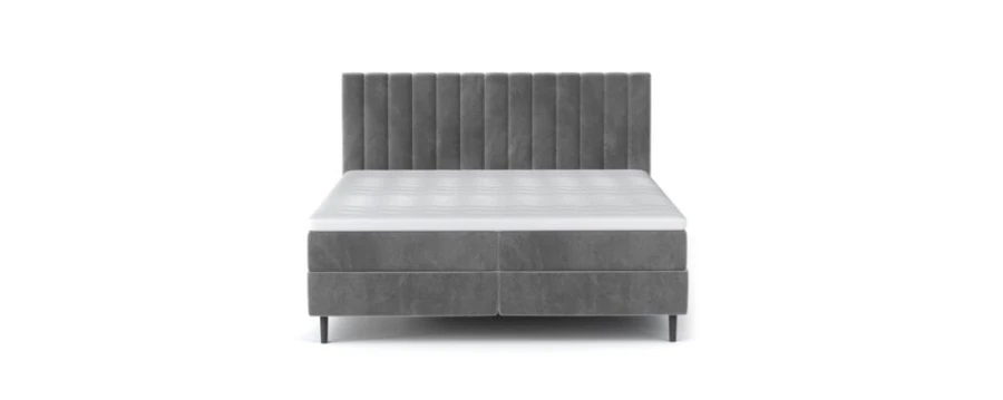 Graues Boxspringbett mit vertikal gestepptem Kopfteil und weißer Matratze in der Frontansicht.