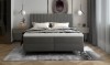 Frontalansicht Boxspringbett grau mit gepolstertem Kopfteil und Teppich im modernen Design.