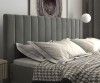 Detailaufnahme vom gepolsterten Kopfteil eines Boxspringbetts mit vertikalen Steppnähten und Kissen.