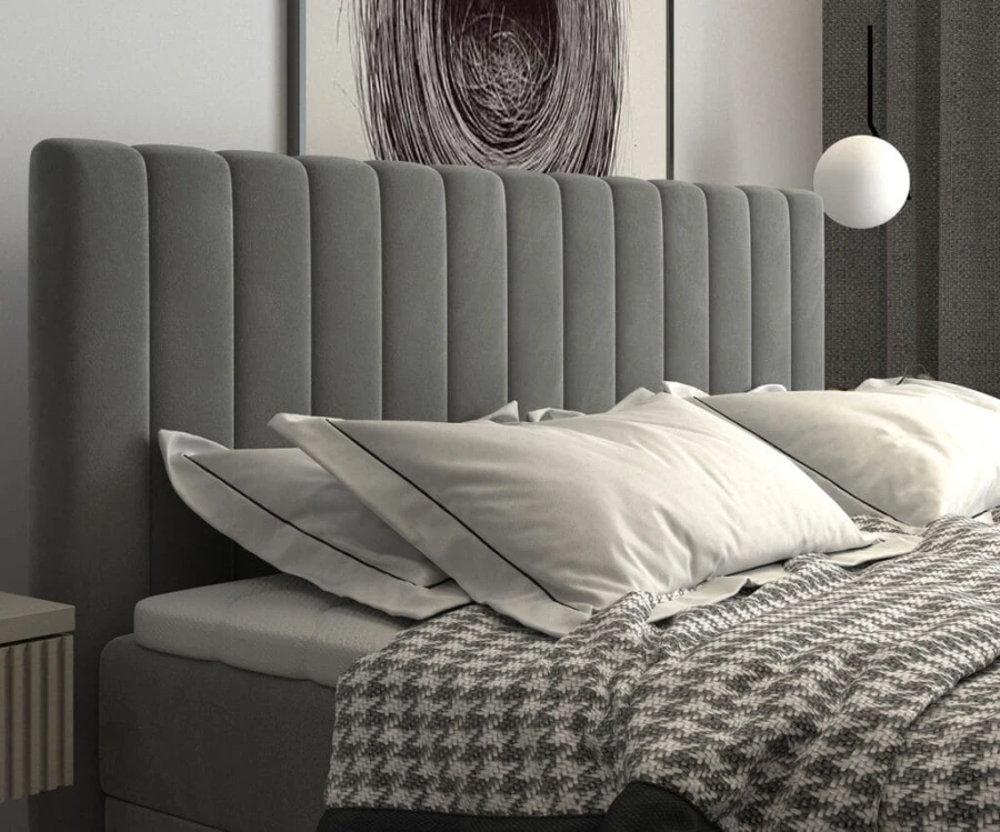 Detailaufnahme vom gepolsterten Kopfteil eines Boxspringbetts mit vertikalen Steppnähten und Kissen.