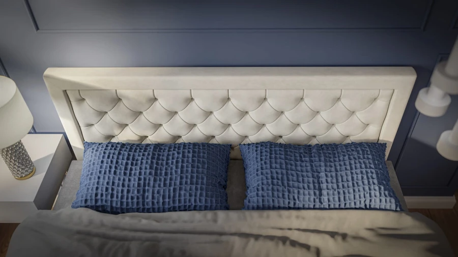 Detailansicht eines cremefarbenen Kopfteils mit Knopfheftung und blauen Kissen.