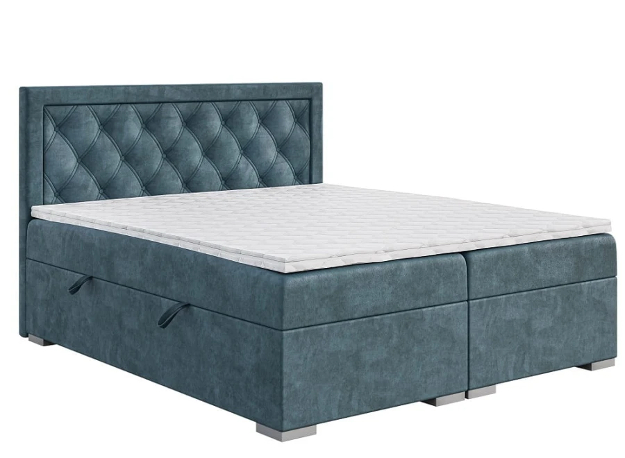 Blaues Boxspringbett mit gestepptem Kopfteil und weißem Topper vor weißem Hintergrund.