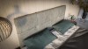 Nahaufnahme eines grauen gepolsterten Kopfteils mit grünen Kissen im modernen Schlafzimmer