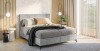 Modernes graues Boxspringbett in einem hellen Schlafzimmer mit Holzpaneelen.