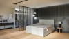 Modernes Schlafzimmer mit hellgrauem Boxspringbett und begehbarem Kleiderschrank hinter Lamellenwand.