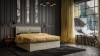 Elegantes beige Boxspringbett mit senfgelber Decke in stilvollem Schlafzimmer-Ambiente.
