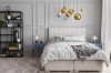 Beiges Boxspringbett in einem modern eingerichteten Schlafzimmer mit grauen Wänden.