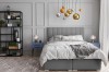 Modernes Schlafzimmer Design mit grauem Boxspringbett und Designer-Lampen.
