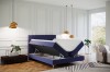 Blaues Boxspringbett mit aufgeklapptem Bettkasten für extra Stauraum im modernen Schlafzimmer.