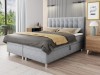 Graues Boxspringbett mit elegantem gestepptem Kopfteil in modernem Schlafzimmer-Ambiente.