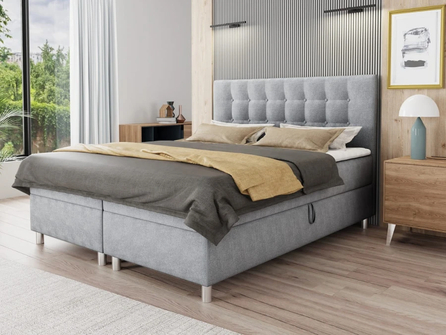 Graues Boxspringbett mit elegantem gestepptem Kopfteil in modernem Schlafzimmer-Ambiente.