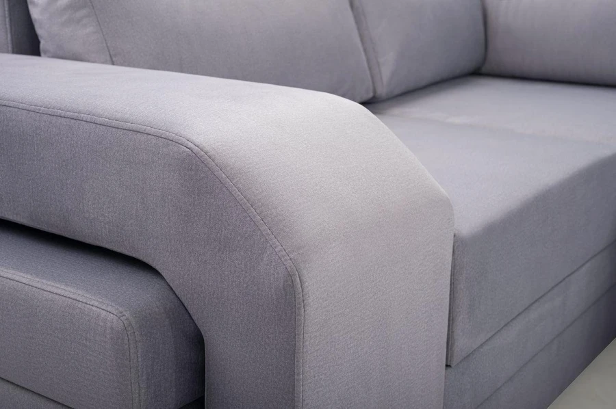 Detailansicht der gepolsterten Armlehne eines grauen Sofas mit hochwertiger Textur.