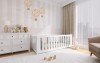 Elegantes weißes Gitterbett für Babys aus Massivholz in einem hellen Kinderzimmer mit Kommode.