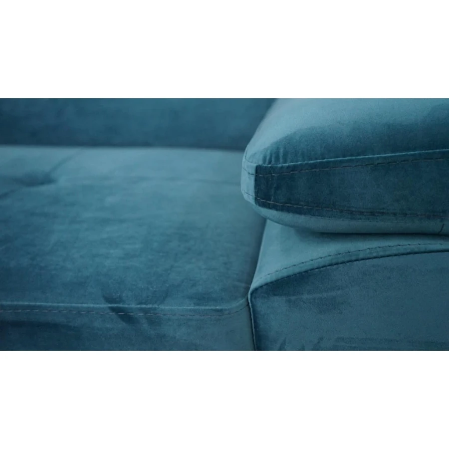 Detailansicht der Armlehne eines blauen Samtsofas mit weichem Bezug.
