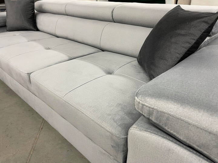Graues Sofa mit weichem Stoffbezug und schwarzen Kissen