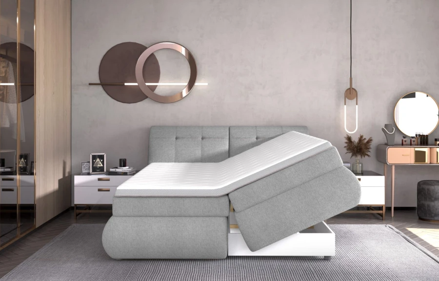 Graues Boxspringbett mit offenem Bettkasten zur Lagerung von Bettzeug im Schlafzimmer.