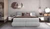 Graues Boxspringbett mit gepolstertem Kopfteil in modernem Schlafzimmer-Interieur.