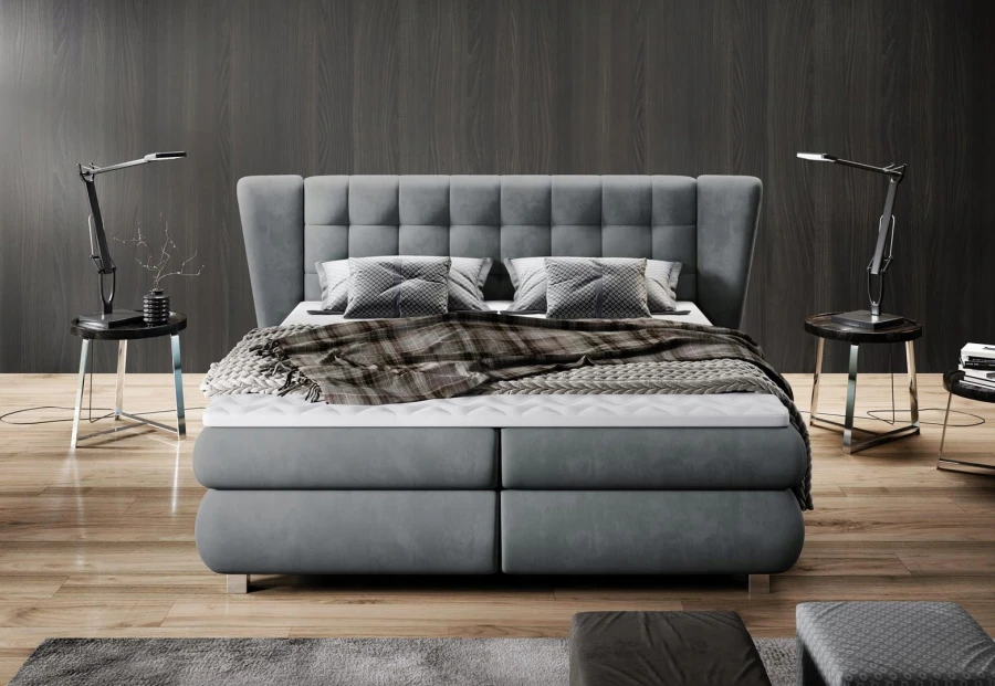 Graues Boxspringbett in Frontalansicht mit hohem, gepolstertem Kopfteil und Nachttischen.