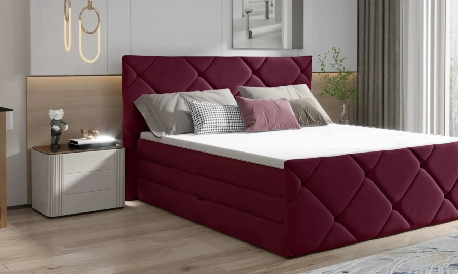 Bordeauxrotes Boxspringbett mit Rautenmuster-Polsterung in einem hellen Schlafzimmer.