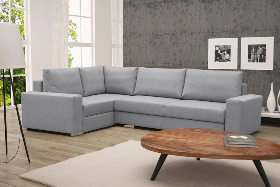 Hellgraues Ecksofa im L-Design vor einer Wand in Betonoptik.