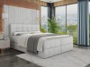 Gemütliches graues Boxspringbett in einem modernen Schlafzimmer mit Panoramafenster.