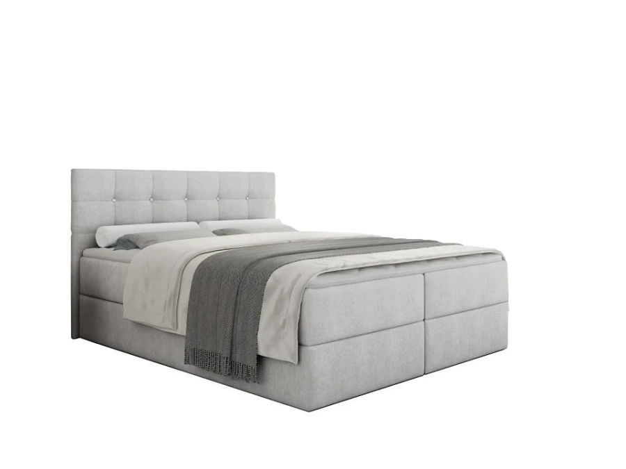 Hochwertiges graues Boxspringbett mit dekorativer Knopfheftung am Kopfteil vor weißem Hintergrund.