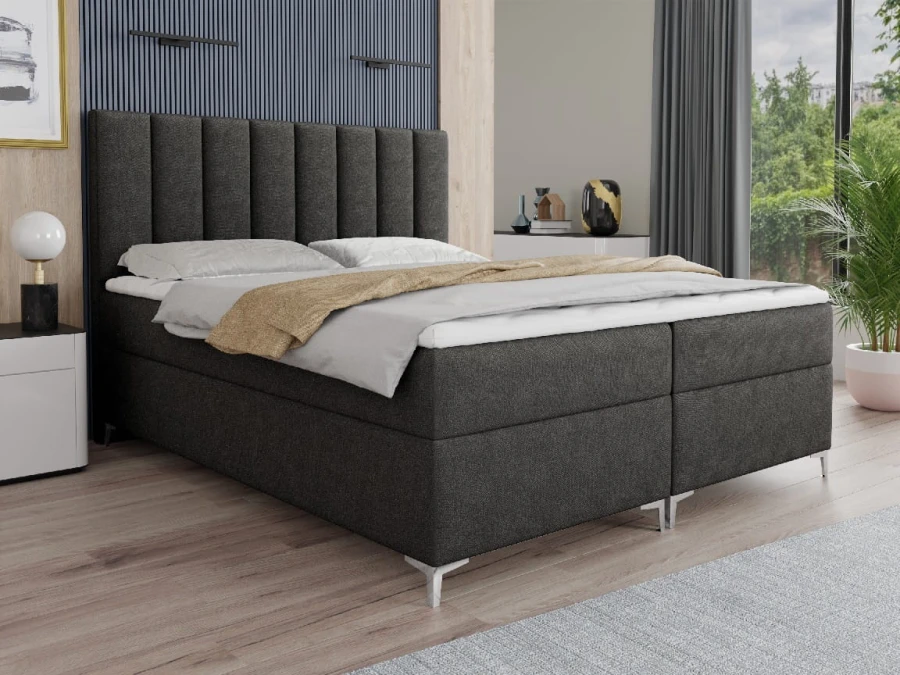Dunkelgraues Boxspringbett mit vertikal gestepptem Kopfteil und Metallfüßen.