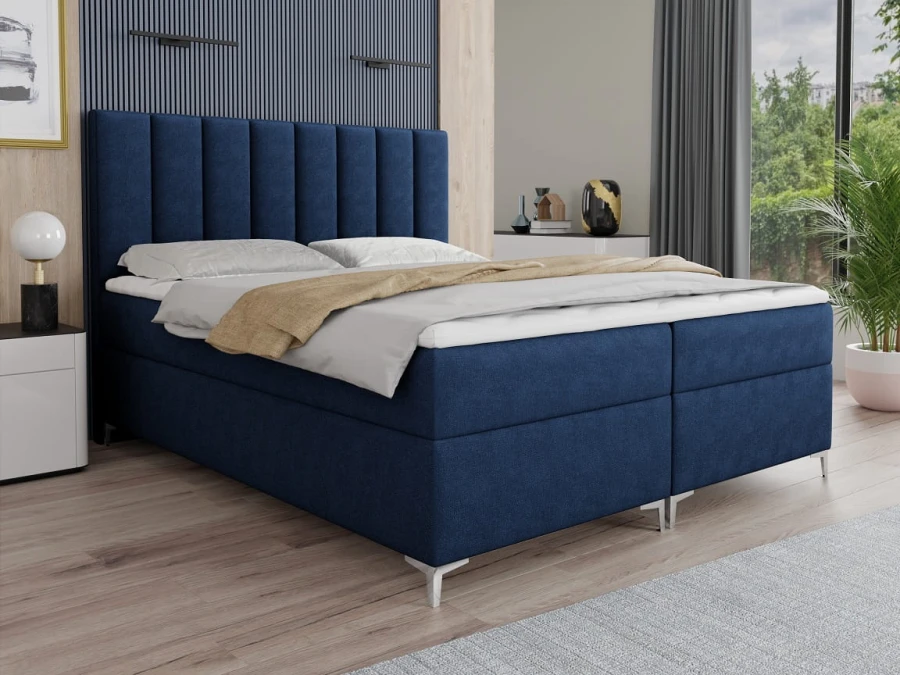 Elegantes blaues Boxspringbett mit hohem Kopfteil in modernem Schlafzimmerambiente.