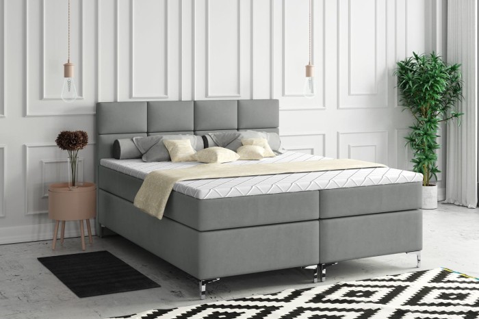 Graues Boxspringbett in modernem Schlafzimmer mit dekorativen Wandleisten und Teppich.