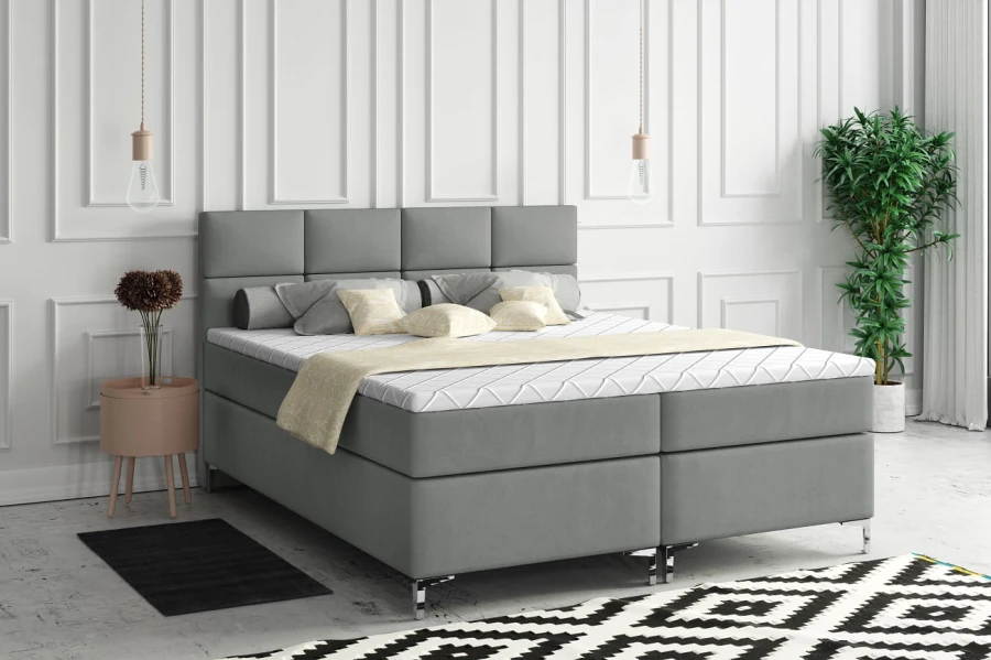 Modernes graues Boxspringbett mit gepolstertem Kopfteil in einem hellen, stilvollen Schlafzimmer.