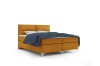 Modernes senfgelbes Boxspringbett mit blauem Plaid vor weißem Hintergrund.