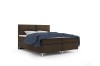 Freigestelltes braunes Boxspringbett mit blauer Decke und Metallfüßen.