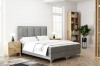 Modernes graues Polsterbett im hellen Schlafzimmer mit Holz-Nachttischen und weißer Bettwäsche.