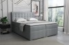 Graues Boxspringbett mit gepolstertem Kopfteil in hellem Raumambiente.