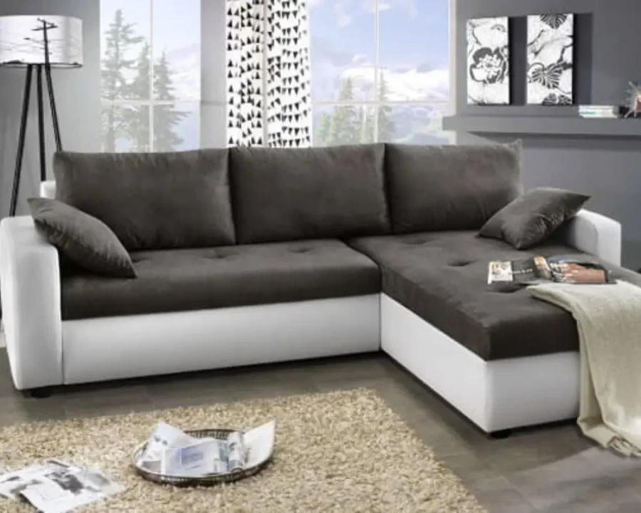 Gemütliches Ecksofa in Grau und Weiß mit Kissen und Decke im modern eingerichteten Wohnzimmer.