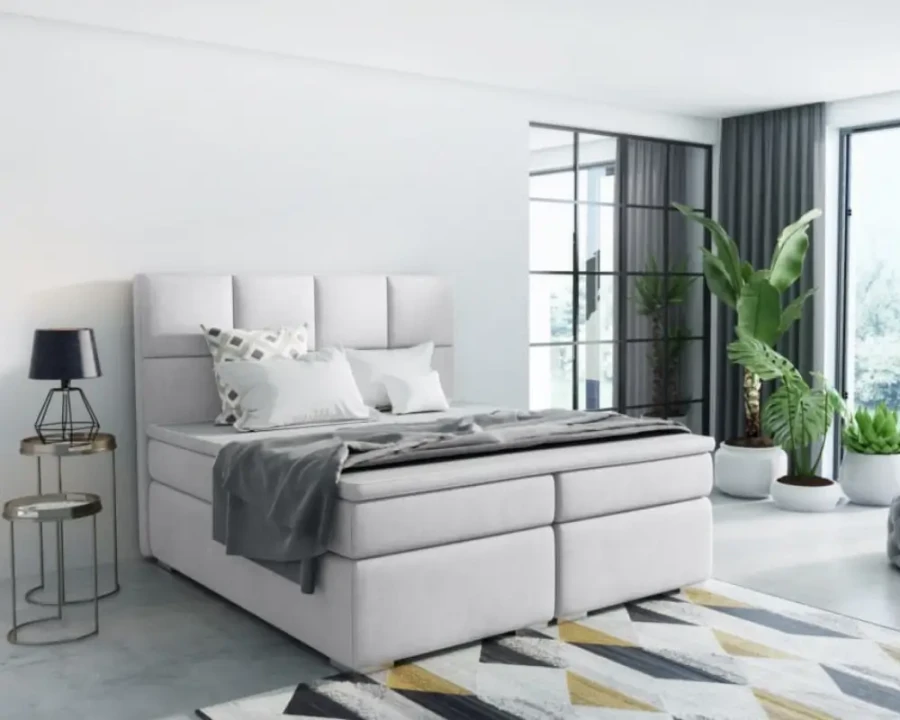 Modernes weißes Boxspringbett in hellem Schlafzimmer mit stilvoller Dekoration.
