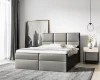 Graues Boxspringbett mit gepolstertem Kopfteil in einem hellen, modernen Schlafzimmer.