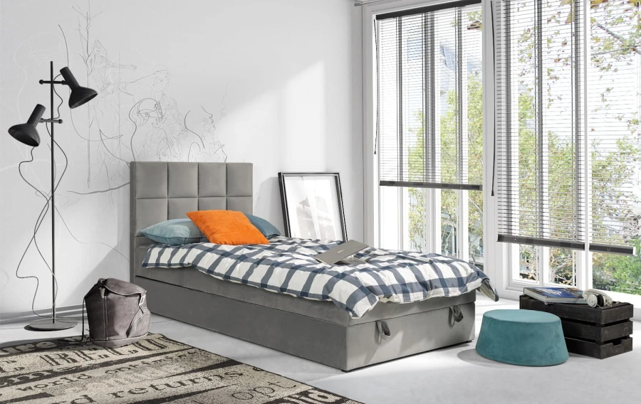 Graues Polsterbett Einzelbett in minimalistischem Schlafzimmer mit Fenster.